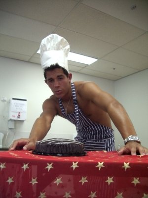Rohan, in Zoolander pose and Naked Chef dress, standing behind a cake.